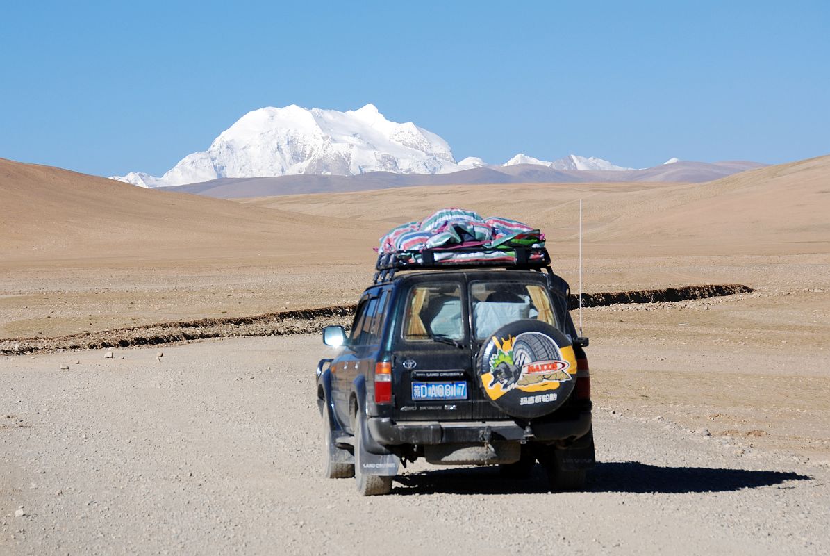 04 Gang Benchen And Our Landcruiser From Between Friendship Highway And Shishapangma Checkpoint Our Landcruiser drives on the road from the Friendship Highway to the west with Gang Benchen ahead.